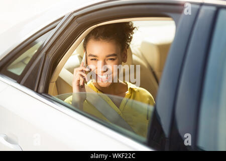 Happy woman sitting in car and talking on phone Banque D'Images