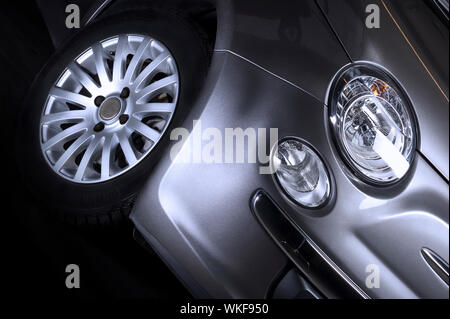 Détail de l'avant , Projecteur feu de stationnement et de pneu d'une voiture d'argent avec un alliage à rayons de roue sport , close up low angle Banque D'Images