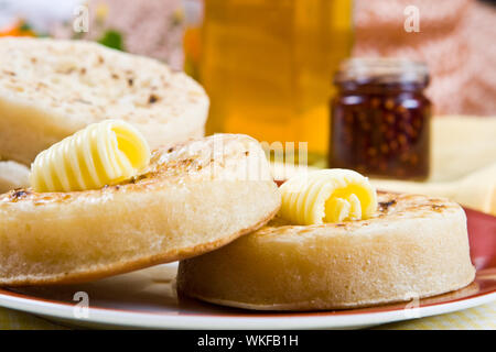 Deux crumpets chauds sur une assiette (bourrage dans l'arrière-plan) Banque D'Images