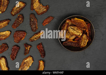 Beaucoup de tomate rouge entière séchée dans flatlay Bol en céramique noir sur gris stone Banque D'Images