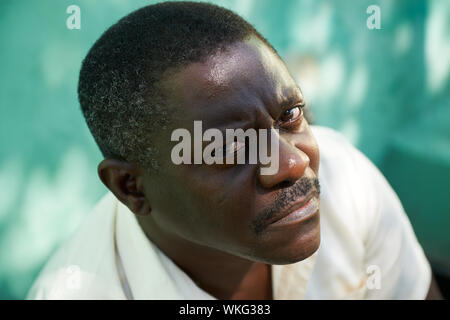 Portrait of mid aged african american man sitting in park et à la recherche à l'appareil photo avec expression triste Banque D'Images
