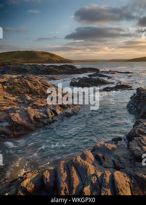 Les rochers autour de Daymer illuminée par le soleil couchant. Brea Hill dans l'arrière-plan et Padstow au loin. Banque D'Images