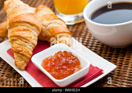 Le petit déjeuner continental avec deux des croissants frais, de la confiture et une tasse de café noir Banque D'Images