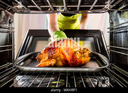 Ménagère prépare le poulet rôti au four, vue de l'intérieur du four. La cuisson au four. Banque D'Images