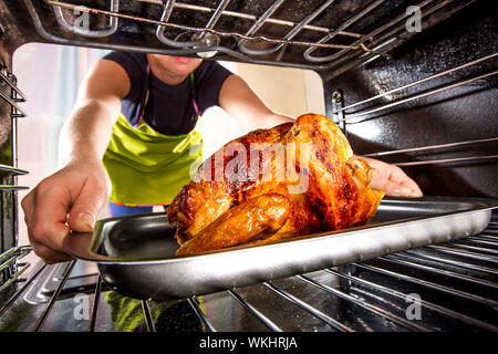 Ménagère prépare le poulet rôti au four, vue de l'intérieur du four. La cuisson au four. Banque D'Images