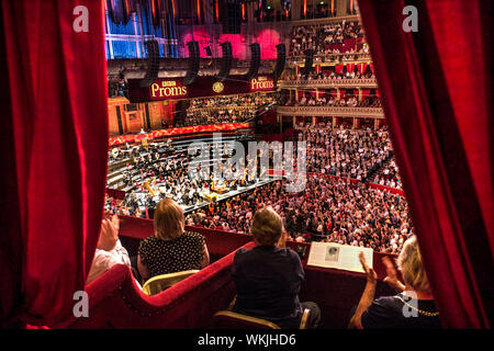 ALBERT HALL INTÉRIEUR Performance BBC Proms avec public applaudissant des mains, Sheku Kanneh-Mason violoncelliste britannique en tenant un arc view de velours rouge de luxe privée à l'auditoire et l'étape de l'orchestre derrière Londres UK dais Banque D'Images