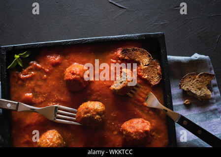 Close-up de boulettes à la sauce tomate sur une plaque noire et d'une table. Voir ci-dessus des boulettes suédoises en sauce épicée. Mise à plat d'un repas mangé. Banque D'Images