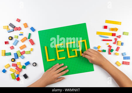 Vilnius, Lituanie - 17 août, 2019 : les mains de l'enfant prendre parole sur la plaque verte à partir de LEGO Lego colorés sur le tableau blanc Banque D'Images