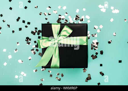 Boîte cadeau noir menthe avec noeud sur fond bleu turquoise avec des paillettes. Maison de concept. Banque D'Images