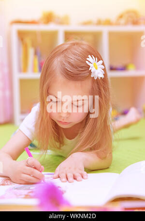 Cute little girl couchée sur le sol et le dessin photo à l'album, s'amusant à la maison, enfance heureuse, avoir le talent de l'art concept Banque D'Images