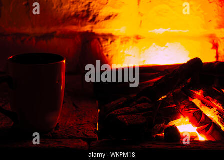 Une tasse de café ou de thé sur une table en bois près de la cheminée dans une pièce sombre. Locations de concept Banque D'Images
