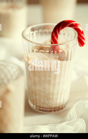 D'hiver traditionnels faits maison délicieux cocktail de Noël avec du lait de poule, le rhum et la cannelle et la muscade décorée canne de Noël sur fond blanc Banque D'Images