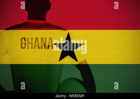 Ghana football player holding ball contre le Ghana drapeau national Banque D'Images