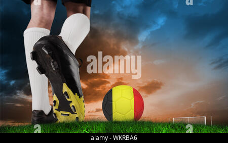 Image composite des coups de chaussure de football balle contre l'Allemagne en vertu de l'herbe verte et bleu ciel orange Banque D'Images