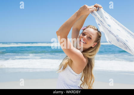 Jolie blonde posing sans souci sur la plage avec un foulard sur une journée ensoleillée Banque D'Images