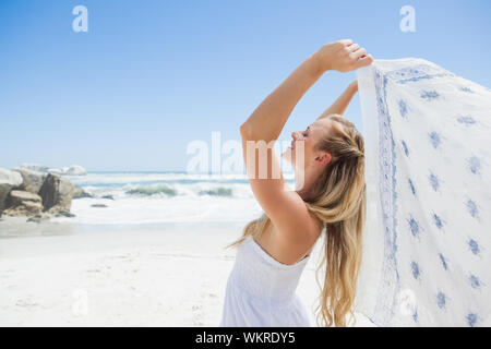 Jolie blonde posing sans souci sur la plage avec un foulard sur une journée ensoleillée Banque D'Images