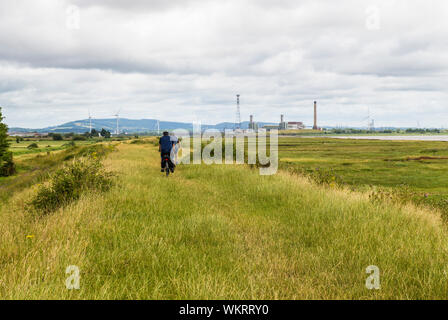 Uskmouth Power Station et deux cyclistes sur la côte du Pays de Galles sur le chemin South Wales Niveaux Gwent Banque D'Images