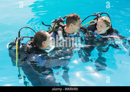 Smiling friends sur formation plongée en piscine lors d'une journée ensoleillée Banque D'Images