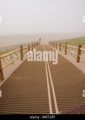 Accès à la plage déserte par jour nuageux dans le New Jersey. Scène de plage déserte pratiquement avec seulement deux personnes à distance. Banque D'Images