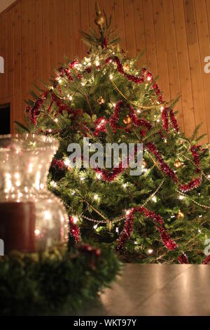 Entièrement décorée d'arbres de Noël naturels et une bougie sur une table à l'intérieur d'un chalet en bois au Canada. Banque D'Images