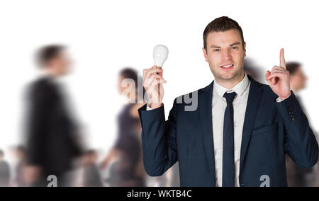 Composite image of businessman holding ampoule et pointant contre groupe de travailleurs Banque D'Images