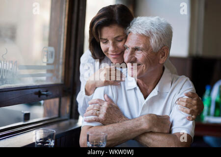 Hauts femme embrasse son mari comme il regarde par la fenêtre d'un café. Banque D'Images