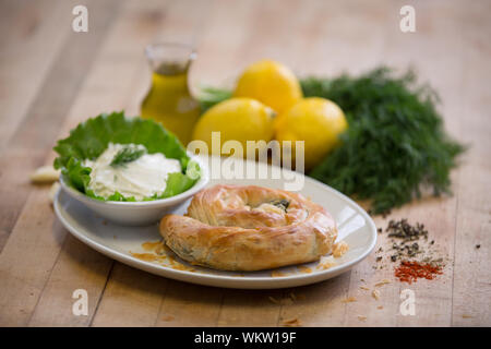 Spanakopita grecs traditionnels servis sur plaque blanche avec sauce au yogourt et citrons Banque D'Images