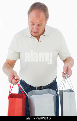 Homme mature regarde ses achats sur fond blanc Banque D'Images