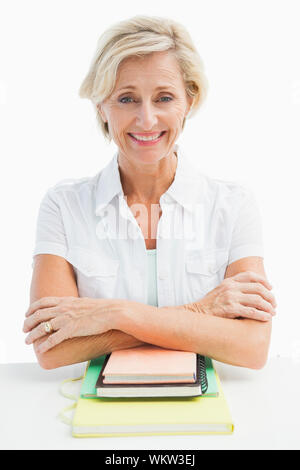 Mature student sitting with notebooks sur fond blanc Banque D'Images