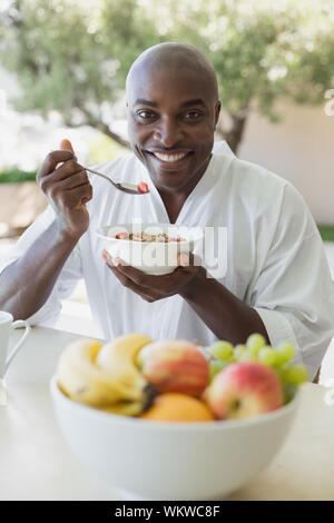 Bel homme en peignoir de prendre le petit déjeuner dehors sur une journée ensoleillée Banque D'Images