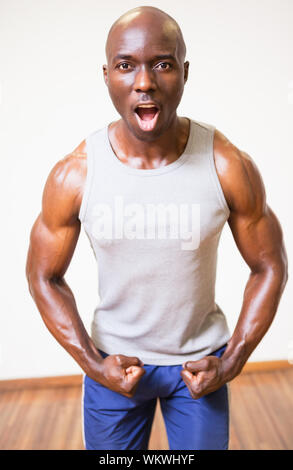 Portrait d'un homme musclé de crier lors de la torsion des muscles en salle de sport Banque D'Images