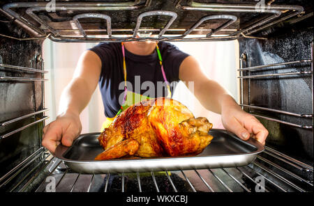 Ménagère prépare le poulet rôti au four, vue de l'intérieur du four. La cuisson au four. Banque D'Images