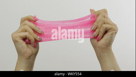 Femme jouant avec les mains étrangement satisfaisant slime rose sur fond blanc. Substance gluante collante. Se détendre et inexplicable du satisfaisant. Super tendance virale sur les médias sociaux pour les choses antistress Banque D'Images