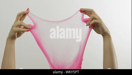 Femme jouant avec les mains étrangement satisfaisant slime rose sur fond blanc. Substance gluante collante. Se détendre et inexplicable du satisfaisant. Super tendance virale sur les médias sociaux pour les choses antistress Banque D'Images