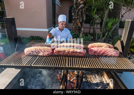 Chef preparing beaucoup de grandes coupes de viande de bœuf sur le grill extérieur par le tabagisme pendant deux heures, puis la cuisson au four pendant encore deux heures Banque D'Images