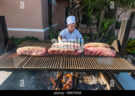 Chef preparing beaucoup de grandes coupes de viande de bœuf sur le grill extérieur par le tabagisme pendant deux heures, puis la cuisson au four pendant encore deux heures Banque D'Images