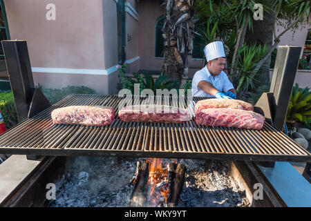 Chef preparing beaucoup de grandes coupes de viande de bœuf sur le grill extérieur par le tabagisme pendant deux heures, puis la cuisson au four pendant encore deux heures Banque D'Images