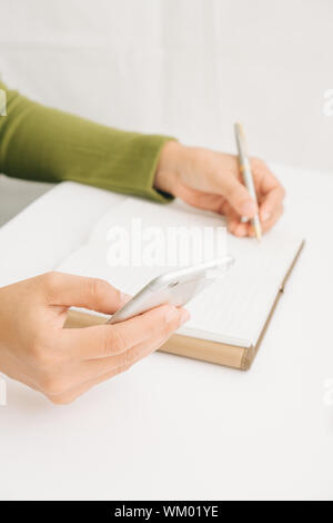Portrait Of Businesswoman Holding Mobile Phone pendant l'écriture de journal à 24