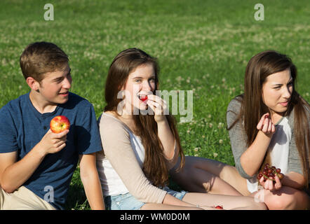 Trio de professionnels Caucasian teenagers eating fruit en plein air Banque D'Images