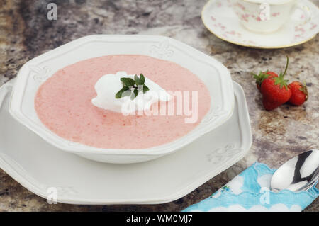 Un bol de soupe de fraises, garni d'une cuillerée de crème fouettée et un brin de menthe fraîche au chocolat. Banque D'Images