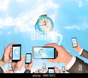 Mains tenant des téléphones intelligents et des vidéos comme réveil. Ciel avec nuages en arrière-plan Banque D'Images
