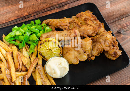 Poisson-frites avec mayonnaise maison sur la plaque noire Banque D'Images