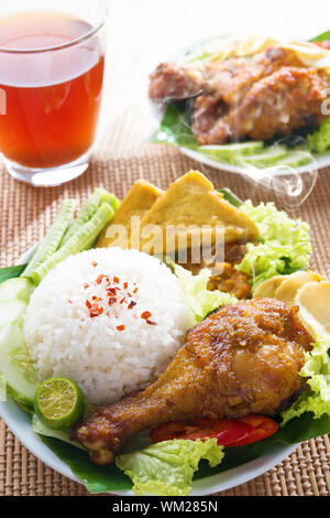 Populaires de la nourriture locale indonésienne nasi ayam penyet, indonésien fried chicken rice. Avec de la vapeur chaude de la fumée. Banque D'Images