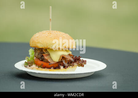 Burger de boeuf au beurre d'herbes, oignons caramélisés, bacon, cheddar, du pain. Banque D'Images