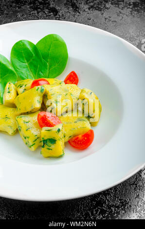 Gnocchi aux épinards avec du beurre fondu et les tomates cerise du jardin Banque D'Images