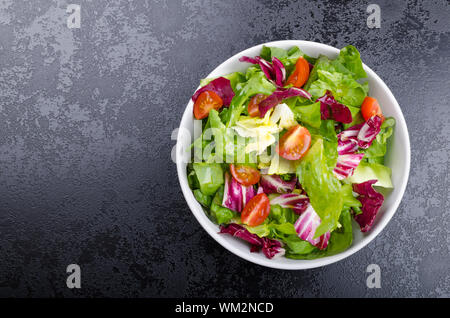 Salade d'endives fraîches avec tomates cerises et sur la plaque noire coin, verser de l'huile d'olive Banque D'Images