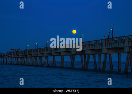 La pleine lune se lève au-dessus de l'Embarcadère de Dania Beach en Floride en tant que pêcheur d'espoir pour une bouchée et les touristes à pied de la jetée. Banque D'Images