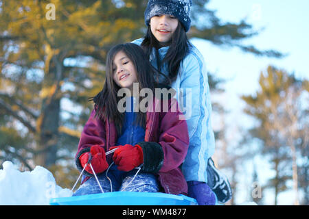 Les enfants en bas de la colline de la luge en hiver Banque D'Images