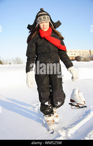 Le patinage sur glace. Femme marche avec des patins de patinage artistique à l'extérieur dans la neige au Québec, Canada. Banque D'Images