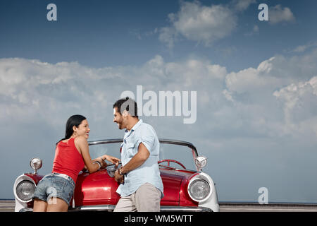 Petit ami hispanique et petite amie, debout près de vintage car à la Havane, Cuba. Vue de côté, de forme horizontale, copy space Banque D'Images